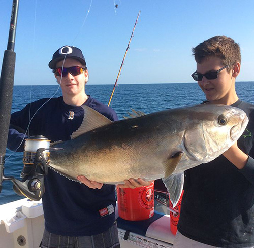 two guys holding a hundred pound Amber Jack
