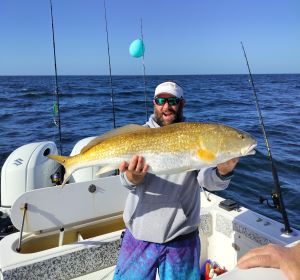 Gentleman sitting in the boat holding a large fish